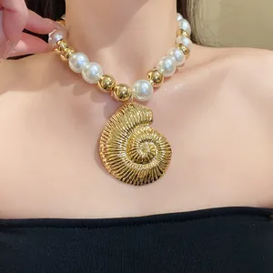 Vista detallada de un elegante collar con perlas blancas y colgante de caracola oro