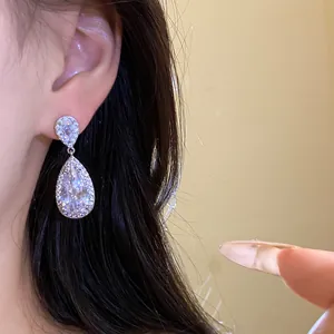 Primo piano dettagliato di eleganti orecchini a goccia in argento con vari zirconi