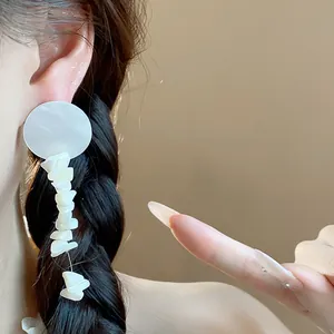 Primer plano de elegantes pendientes colgantes de concha blanca irregular en un modelo
