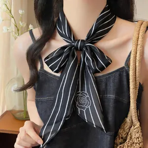 Detail view of a black and white striped neck scarf tied in a bow with a rose pattern.
