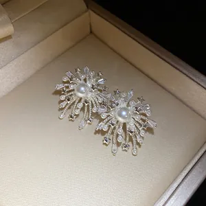 Close-up of firework-shaped earrings with pearls and shimmering zircons