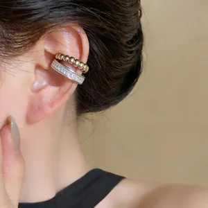 Detail view of a silver-toned cubic zirconia ear cuff and gold beaded earring set