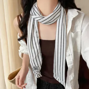 Detailed shot of a minimalist black and white striped neck scarf with a delicate rose print