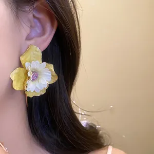 Primer plano de un elegante pendiente de flor amarillo y blanco con un detalle brillante