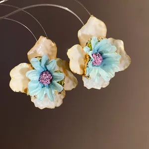 Primer plano de aretes de flores azules y crema para las vacaciones de verano