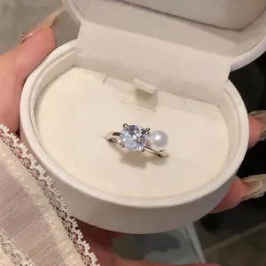 Elegant silver ring featuring a large clear crystal and a white pearl in a luxury box