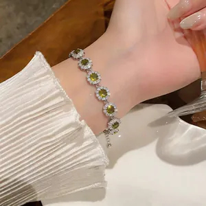 Dettaglio di un bracciale in argento scintillante con pietre verdi tonde e cristalli