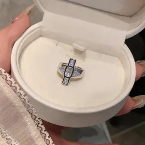 Close-up of silver geometric ring with clear gemstones in white velvet jewelry box