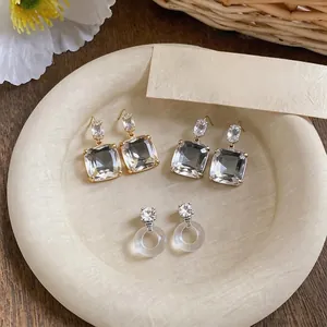 Elegant 18k gold plated silver needle zircon earrings set on a textured plate