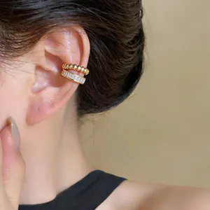Close-up detail shot of elegant gold beaded and baguette-cut zircon ear cuffs on ear