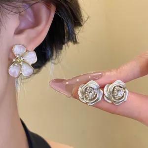 Close-up view of elegant floral stud earrings with sparkling crystals and pink enamel