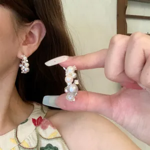 Detail of elegant French luxury hoop earrings featuring clusters of white pearls and zircons