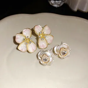 Detailed view of elegant pink enamel flower earrings and silver rose heart pearl studs.