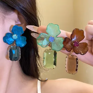 Close-up of stylish acrylic flower drop earrings in vibrant blue, green, and brown colors