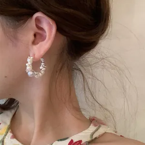 Detailed macro view of French style hoop earring with pearls and zircons on ear