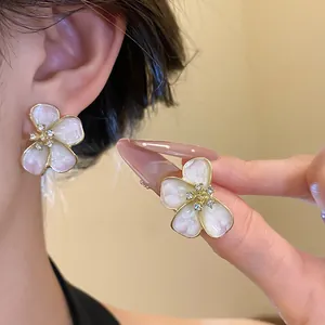 Detail view of pink enamel flower stud earrings with crystal center and gold edge