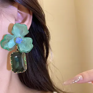Close-up of mint green acrylic flower earrings with emerald green crystal pendant.