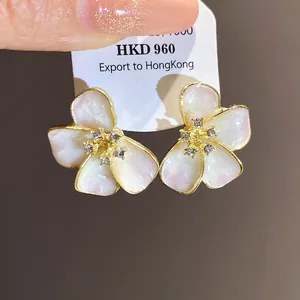 Close-up of elegant flower stud earrings with rhinestone centers and enamel finish