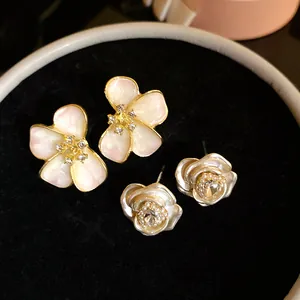 Close-up of elegant flower stud earrings with enamel and sparkling crystal centers.