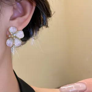 Close-up of elegant flower stud earrings with pearl-like petals and diamond center