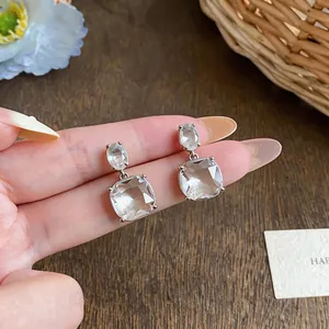 Detail of 18K gold plated silver needle earrings with clear square cubic zirconia stones.
