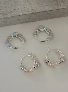Detail view of elegant C-shaped hoop earrings featuring pearls and colorful beads.