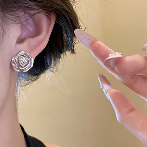 Close-up detail of elegant silver flower stud earrings with a heart crystal center.