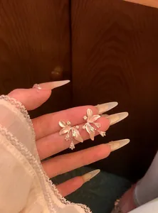 Dettaglio di eleganti orecchini a fiore con gocce di zircone e petali smaltati lucidi