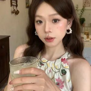 Close-up of pearl and cubic zirconia hoop earrings worn by a model in a warm cafe