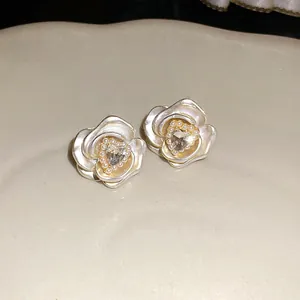 Close-up of elegant rose flower stud earrings with heart crystal and micro pearls