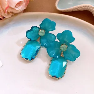 Close-up detail of blue acrylic flower earrings with faceted rectangular gem drops