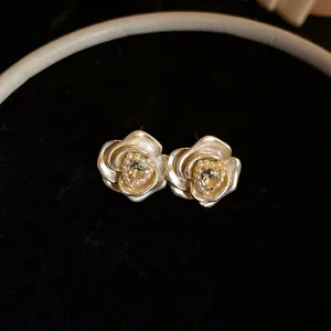 Close-up macro view of elegant matte silver rose stud earrings with pearls and crystals