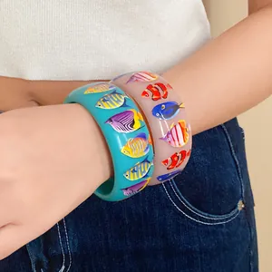 Detail view showing colorful tropical fish prints on wide resin vacation bangles