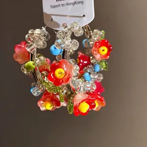 Handmade glass beaded floral hoop earrings with silver needles in a vibrant forest style