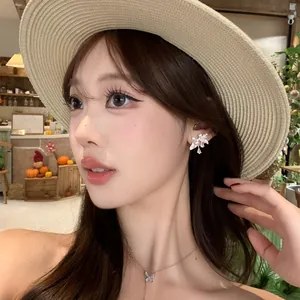Dettaglio di orecchini a fiore con zirconi su modella con cappello