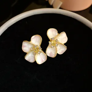 Close-up of flower stud earrings with pearlescent enamel petals and crystal centers