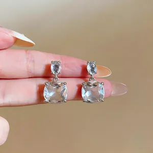 Elegant clear cushion-cut drop earrings with silver finish shown in close-up detail.