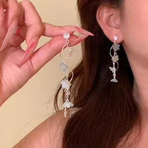 Close-up of long tassel earrings with sparkling zircon and delicate flower charms