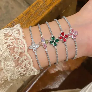 Close-up detail of elegant four-leaf flower bracelets with colorful zircon stones on female wrist