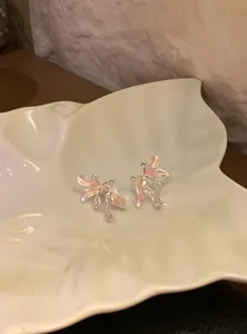 Dettaglio di orecchini a lobo a forma di fiore con zirconi e petali in smalto rosa