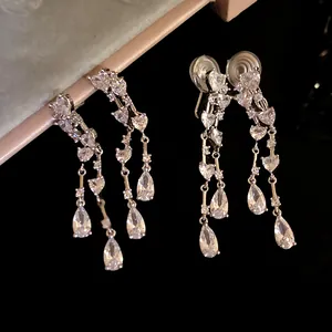 Primo piano di orecchini a nappa argentati con pietre a cuore e a goccia brillanti.