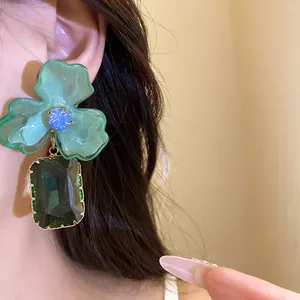Detailed view of green acrylic flower earrings featuring a dark green gemstone pendant
