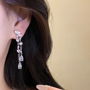 Primo piano di eleganti orecchini a nappa lunga con zirconi a cuore e a goccia d'acqua.