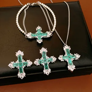 Detailed close-up of luxurious green zircon cross necklace, pearl bracelet and earrings set
