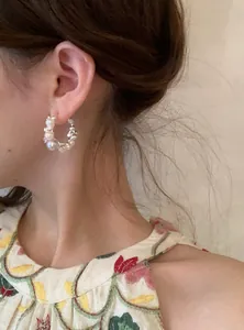 Detailed close-up view of an elegant pearl and zircon hoop earring worn on a model's ear