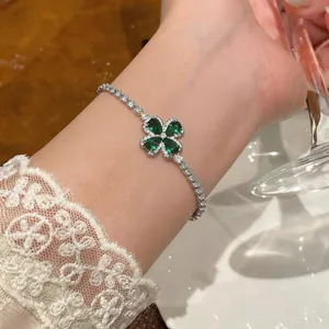 Close-up of a silver-toned bracelet featuring a green zircon four-leaf clover centerpiece.