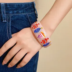 Close-up of resin wide bangle featuring colorful tropical fish print on model's wrist