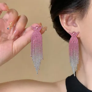 Primo piano di eleganti orecchini a nappa con strass sfumati rosa a croce a X