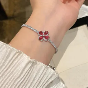 Elegant silver bracelet with red zircon flower charm worn on wrist