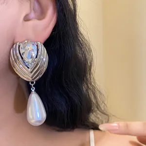 Dettaglio di orecchini a goccia in argento con strass e grande perla bianca